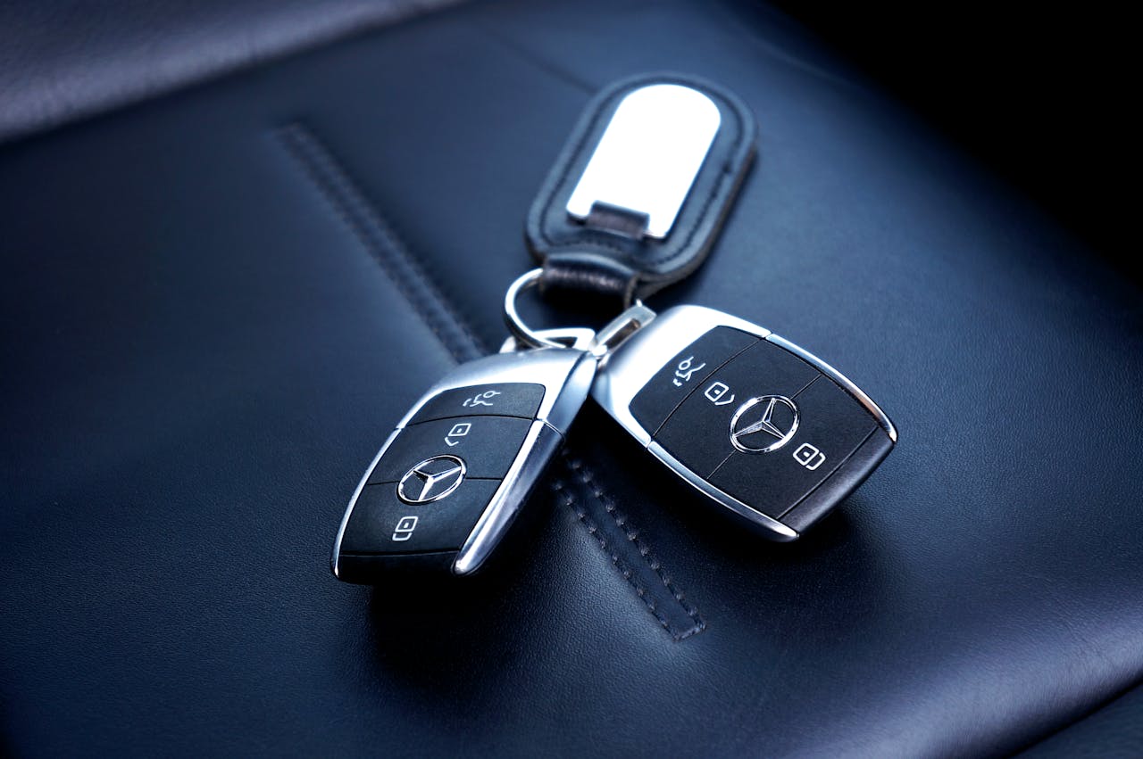 gallery-04 Two Mercedes Benz car keys resting on a luxurious leather seat, showcasing elegance and design.