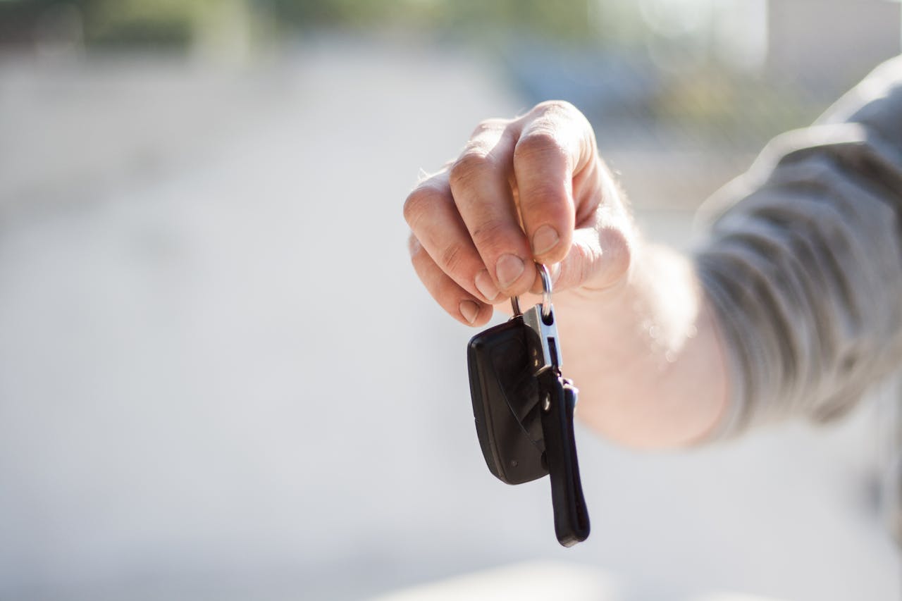 about-img-01 Close-up of a hand handing over car keys, signifying purchase or rental.