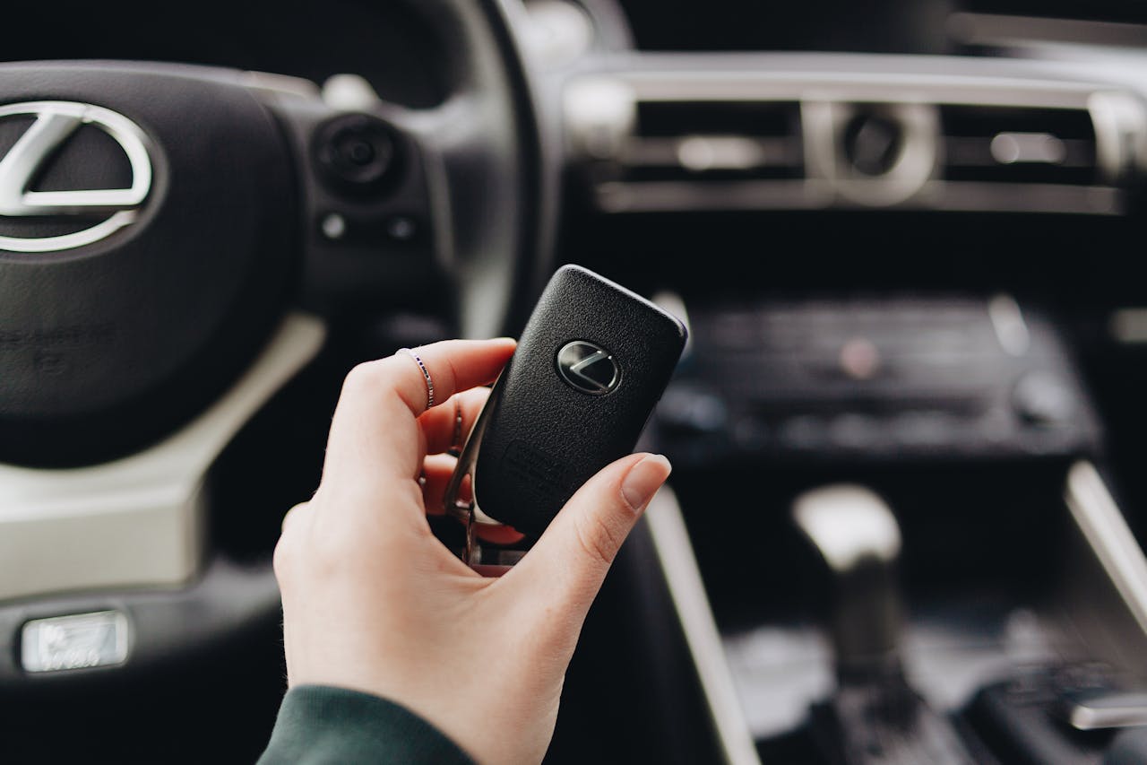 about-us Person holding a Lexus car key inside a luxury vehicle's interior, showcasing brand elegance.
